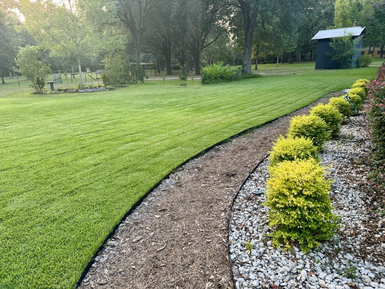 Thick striped lawn with clean landscape bed edges, treated by Stewart Pest Control